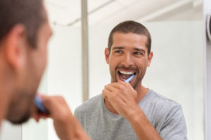 Smiling young man with toothbrush cleaning teeth